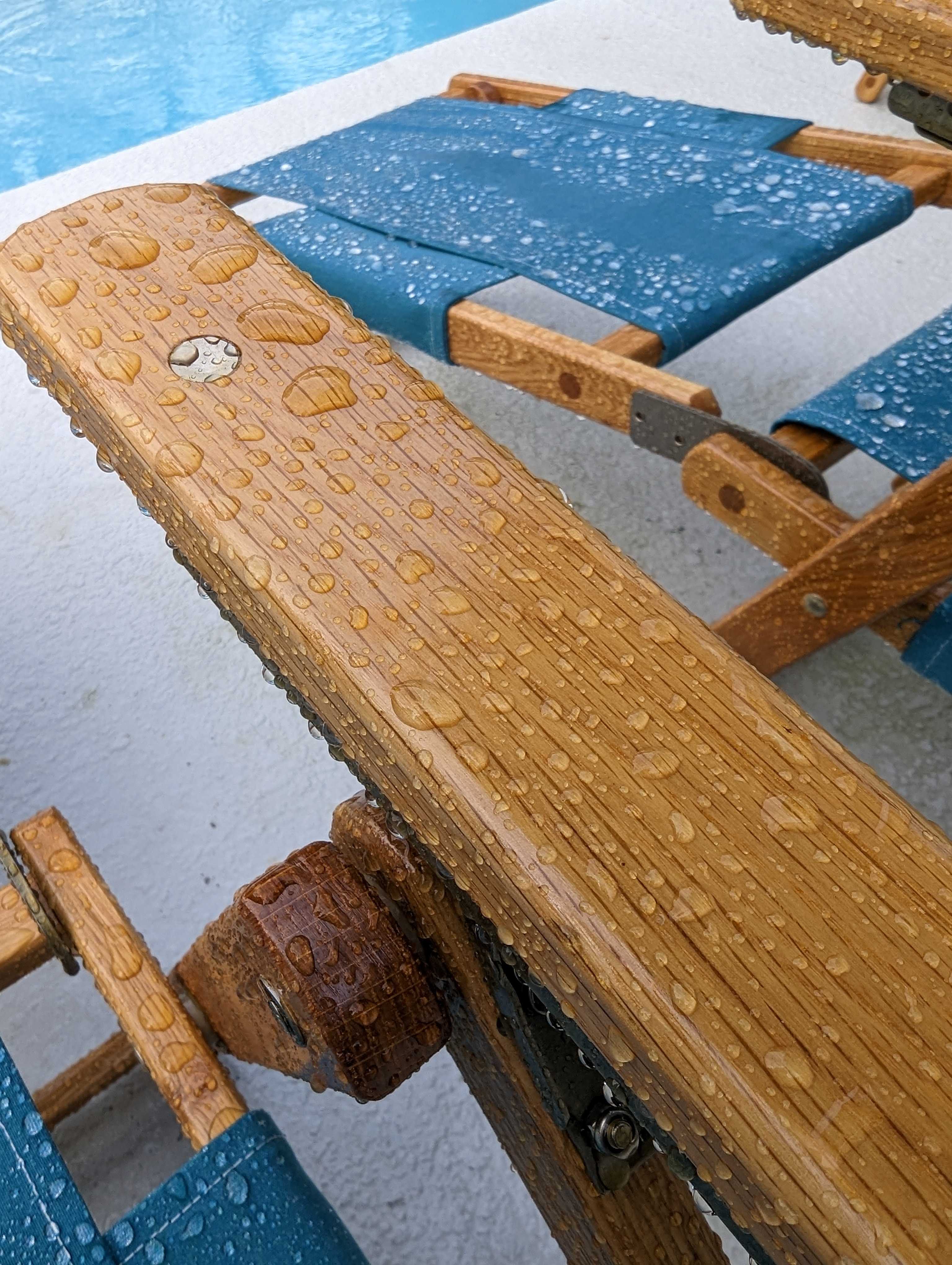 Water beading on an oak armrest beside teal canvas